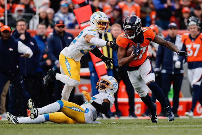 Denver Broncos wide receiver Lil'Jordan Humphrey (17) runs through the tackle of Los Angeles Chargers safety Alohi Gilman (32) and cornerback Essang Bassey (27) in the second quarter at Empower Field at Mile High.